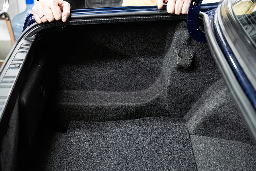 Technician installing replacement automotive carpet at Santa Cruz Auto Upholstery in Phoenix, Arizona.